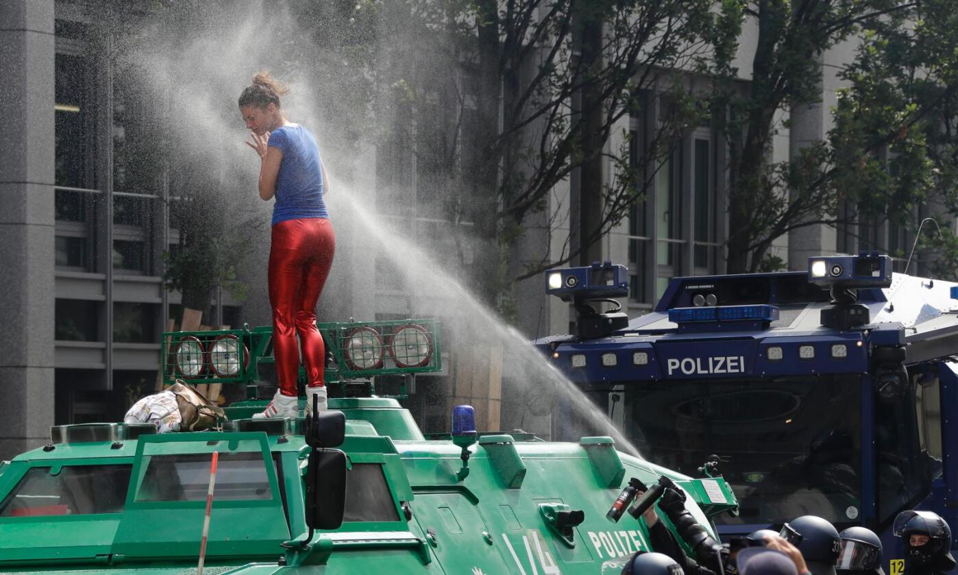 Pepperspray: En kvinne i røde bukser «åpnet» G20-toppmøtets første dag med å få en pepperspray-dusj etter å ha klatret opp på en pansret politibil. Så ble det bare verre. Foto: AP Photo / Matthias Schrader / NTB scanpix