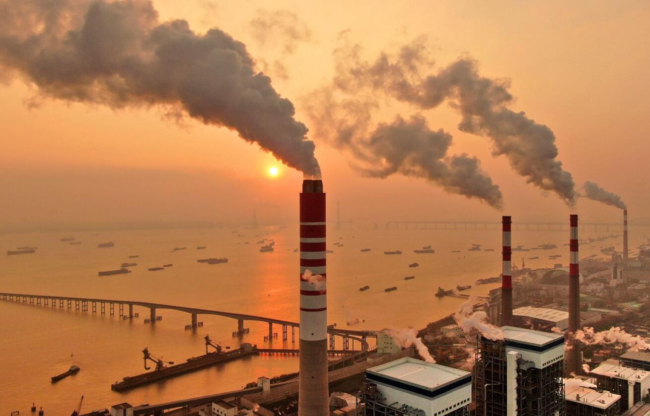 Solnedgang bak et kullkraftverk ved elva Yangtze i Nantong i Kina. Forbrenning av kull er en av de største kildene til menneskeskapte CO2-utslipp. Foto: Chinatopix / AP / NTB