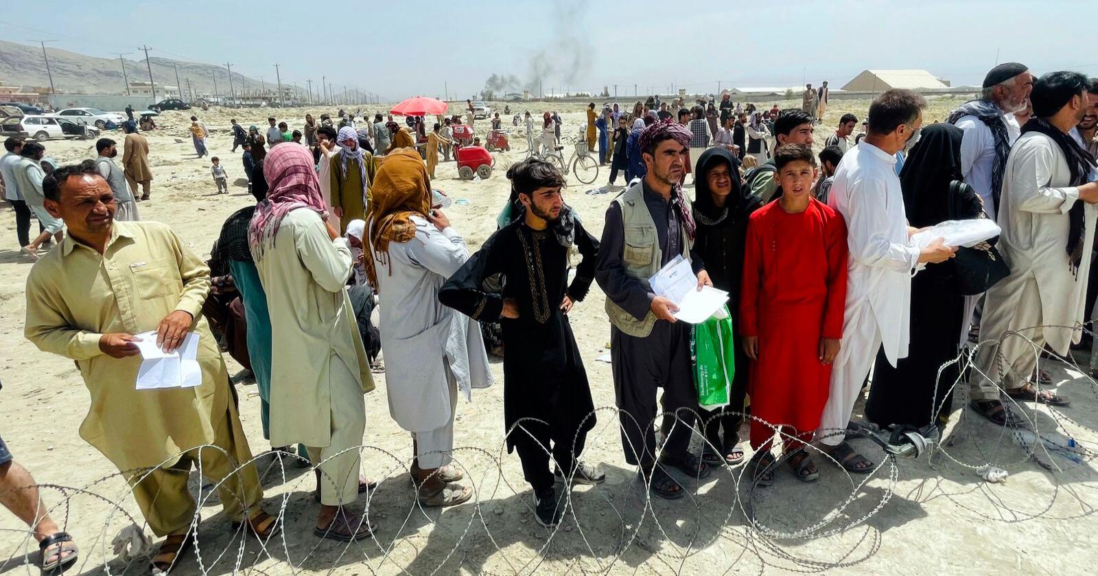 Hundrevis av afghanere ved Hamid Karzai-flyplassen i midten av august. Mange fikk ikke tatt seg ut av landet, og FN frykter at matlagrene de har der kan gå tomme innen slutten av måneden. Foto: AP / NTB
