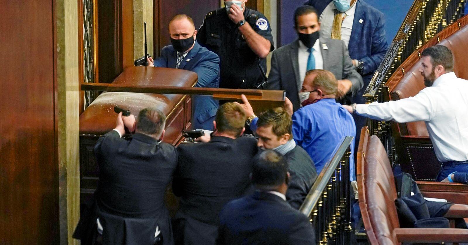 Våpenmakt: Polititjenestemenn har trukket pistol for å holde inntrengende demonstranter ute av Representantenes hus på Capitol. Foto: AP Photo/Andrew Harnik