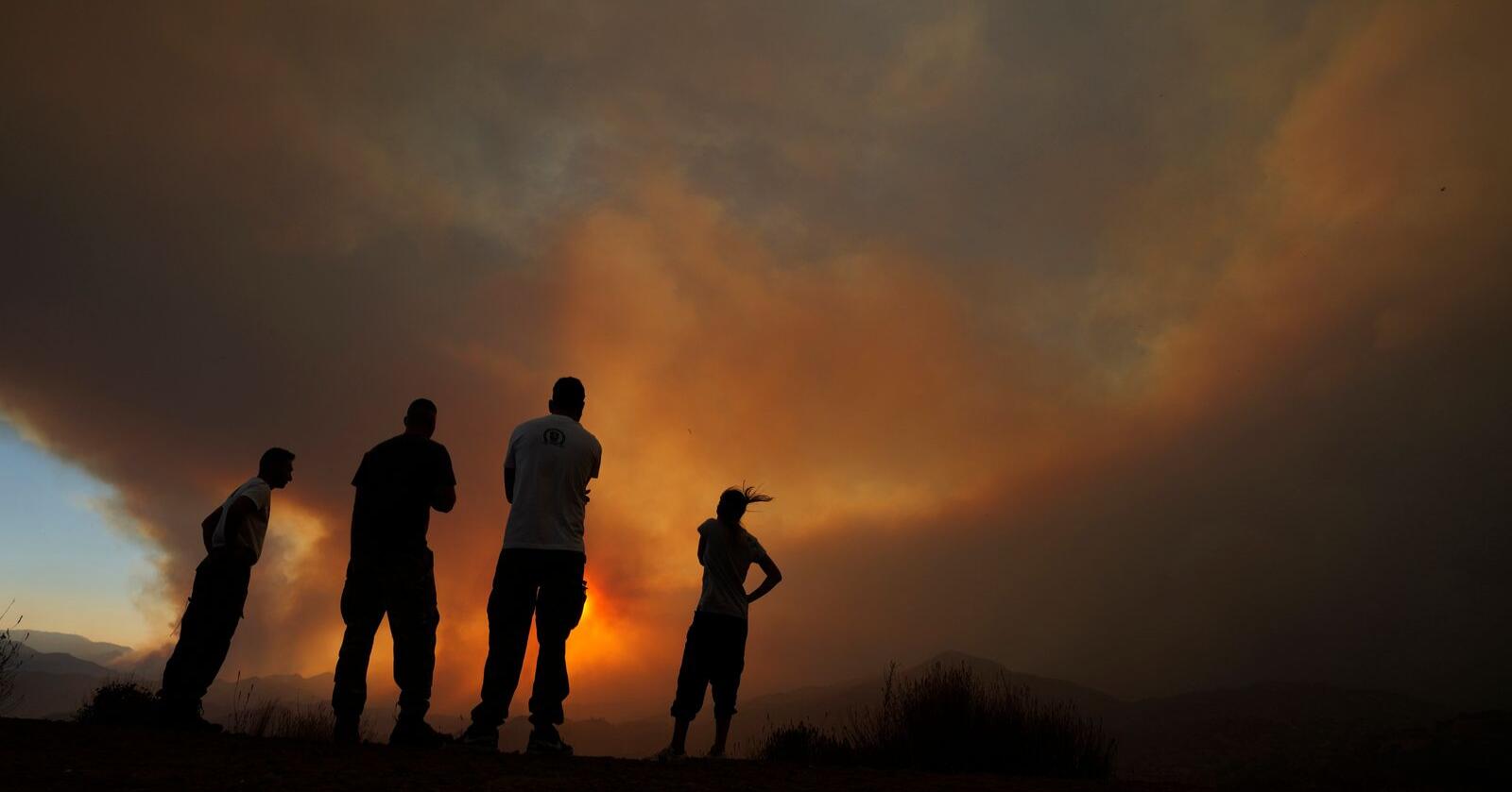 Innbyggere ser på brannen som herjer i et fjellområde ved Larnaka. Foto Petros Karadjias / AP / NTB