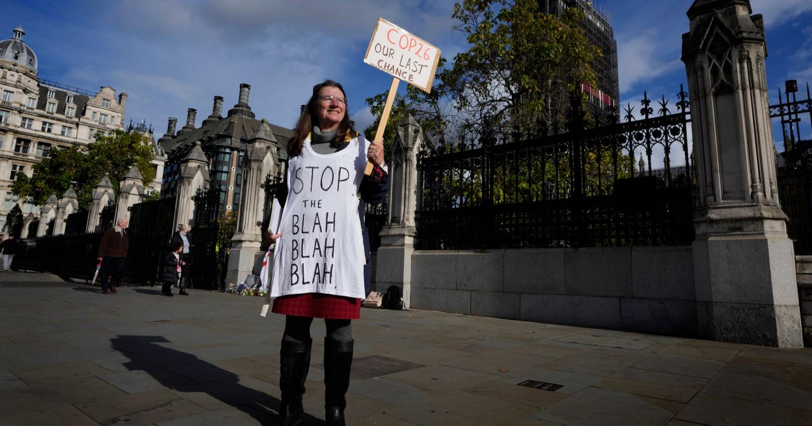 En enslig klimademonstrant holder opp en plakat utenfor parlamentsbygningen i London. Søndag åpner klimatoppmøtet COP26 i Glasgow. Foto: Kirsty Wigglesworth/AP/NTB