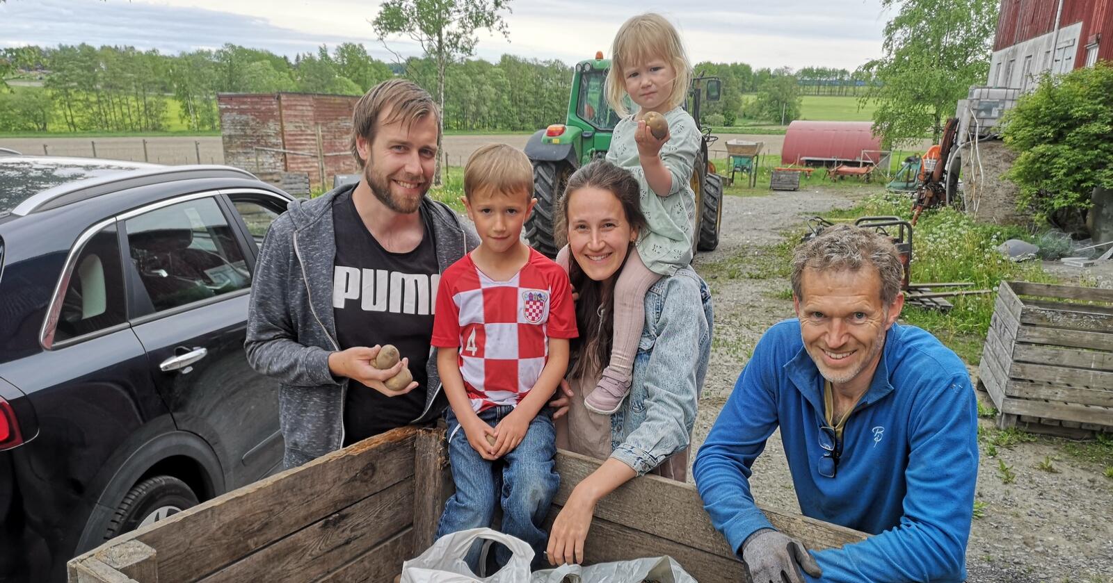 Øyvind Røed og Sara Sumic med barna Sindre og Ane henter gratis poteter hos Svein Stene (t.h) via appen Fuud. Foto: Marit Hilsen. 