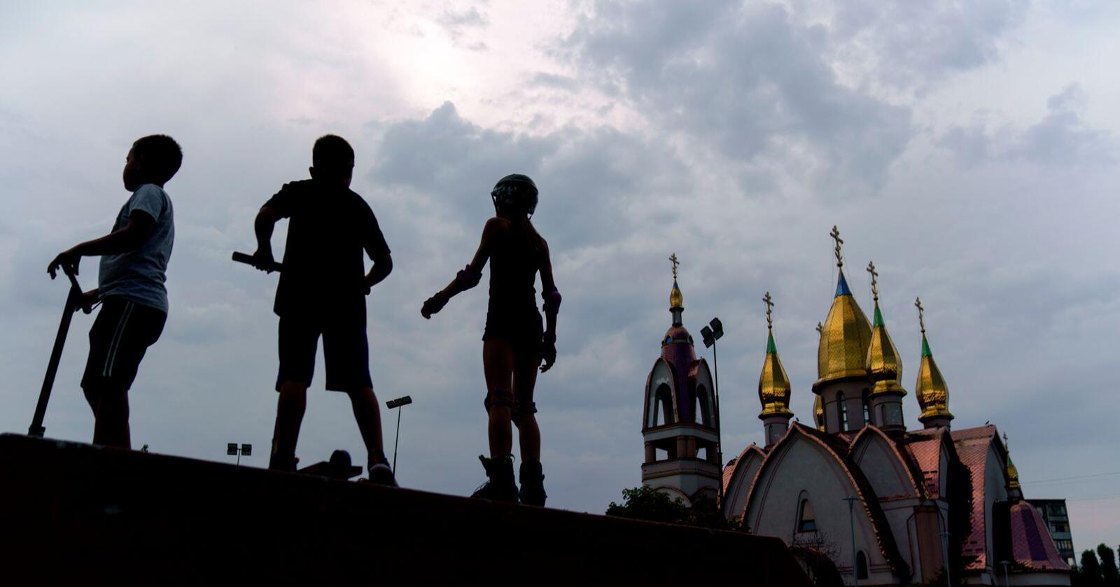 Barn som leker ved en skateboardpark like ved den ukrainske ortodokse kirken i Dnipro. Foto: David Goldman/AP photo/NTB